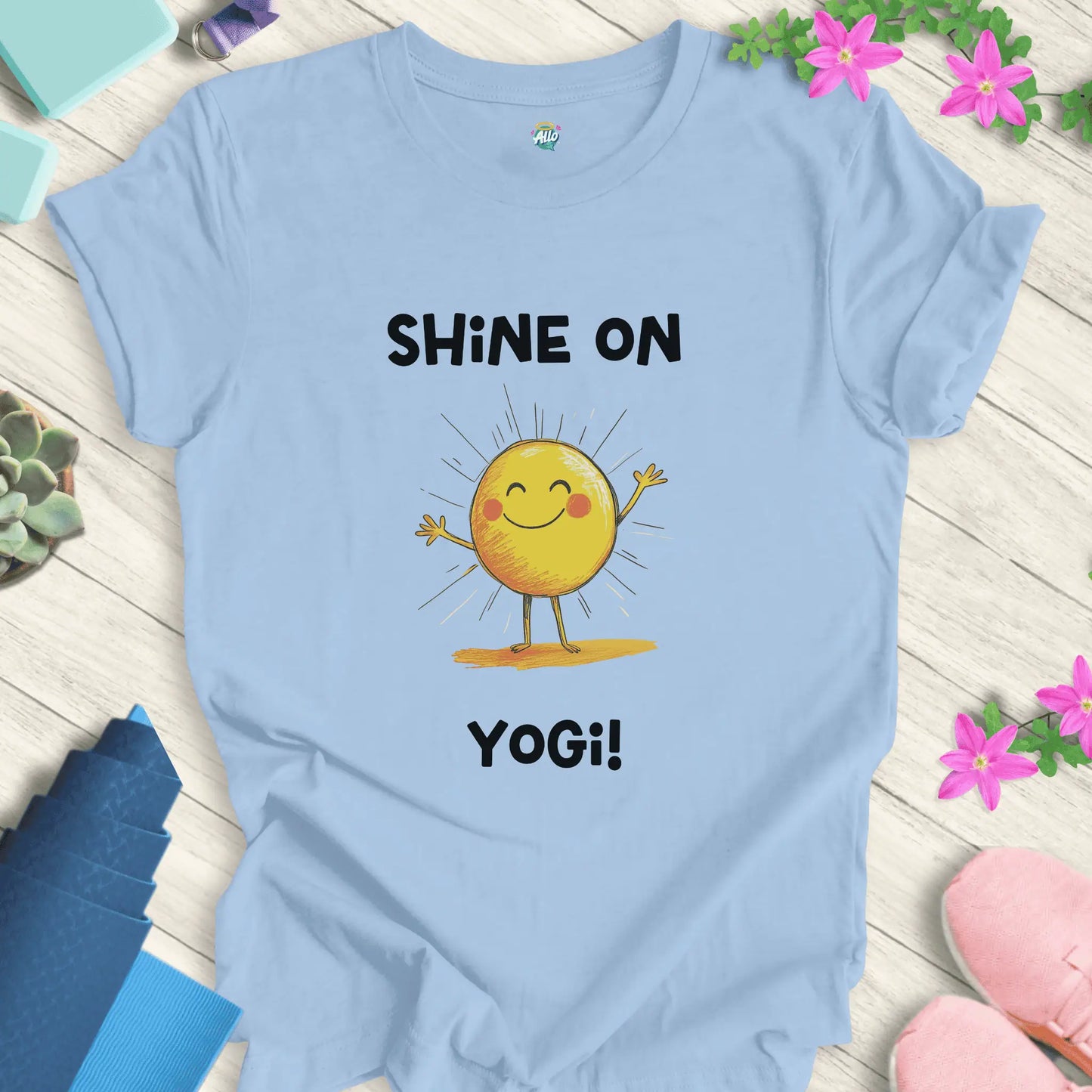 Baby Blue yoga t-shirt with 'Shine On Yogi!' text and cheerful sun design by Halo Allo, perfect for meditation and spiritual wellness.