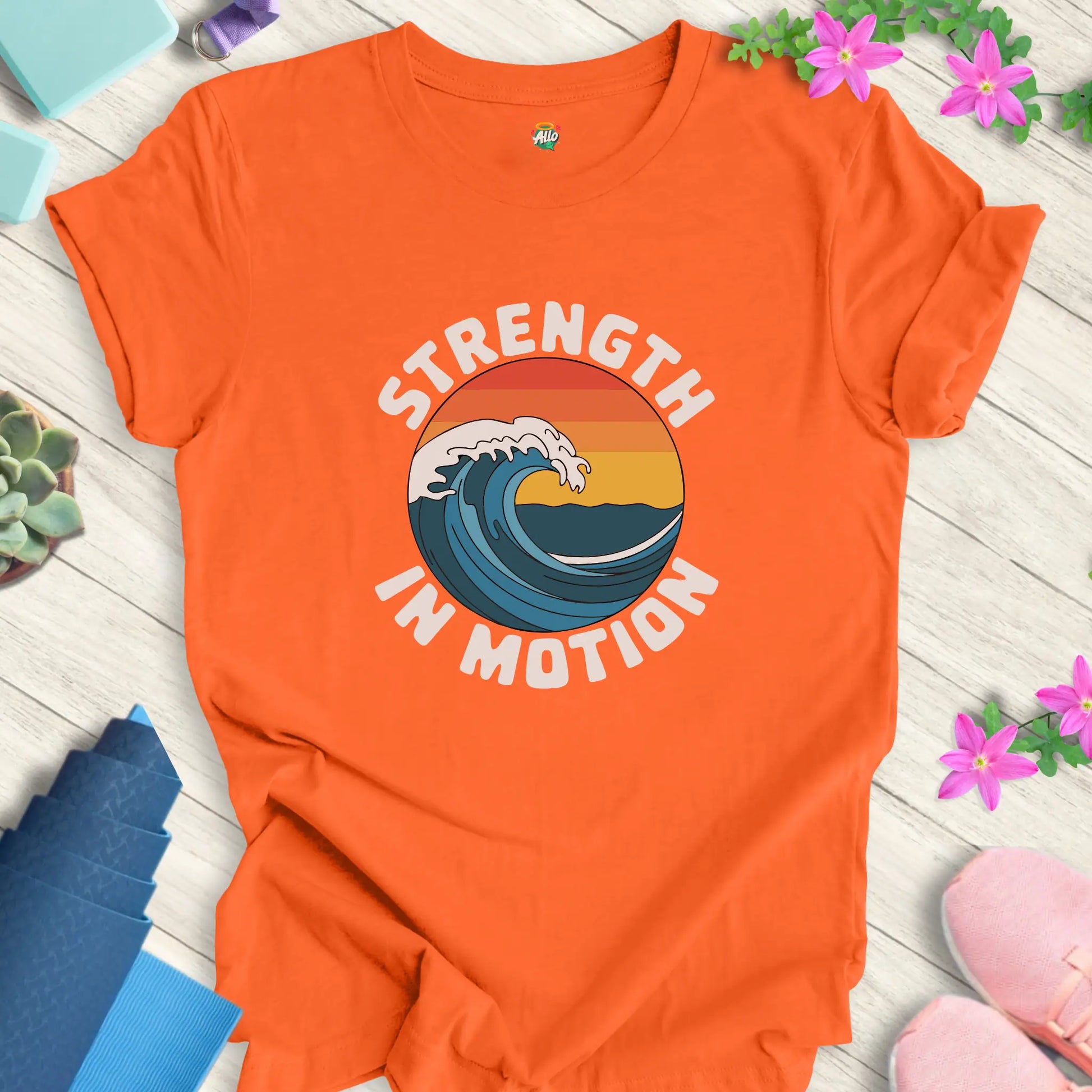 Orange yoga t-shirt with 'Strength In Motion' design by Halo Allo, featuring a wave graphic. Perfect for meditation and mindfulness.